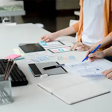 Documents and designs scattered over a desk whilst being reviewed.