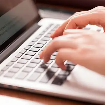 Close up of hannds typing on a laptop keyboard.