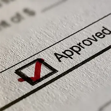 Close up of a document marked approval and a red tick.