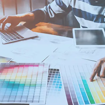 Colour charts scattered over a desk being reviewed.