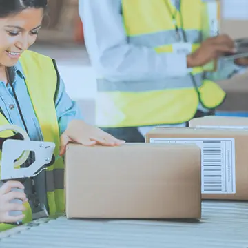 A woman taping up a box ready for shipping in a warehouse.